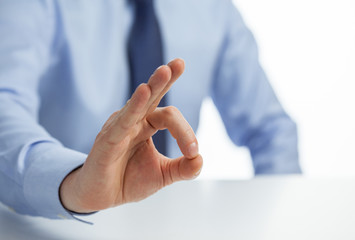 Naklejka premium Unrecognizable businessman showing OK sign sitting at the table