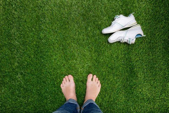 Feet resting on grass with slying sneakers