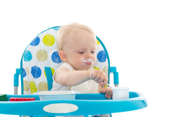 Sweet baby with spoon eats the yogurt.