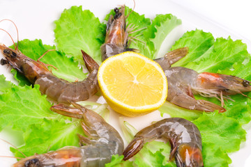 Raw shrimps on plate with lettuce