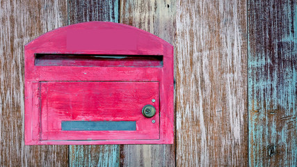 red wooden mail box on wooden wall.