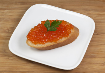 Tasty sandwich with red caviar on plate
