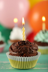Delicious birthday cupcakes on table on bright background