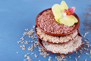 Different types of rice in bowls on wooden background