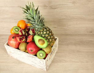 Assortment of exotic fruits in box on wooden background