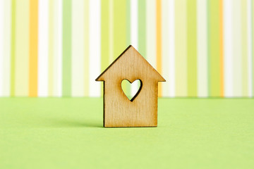 Wooden house with hole in the form of heart on green striped bac