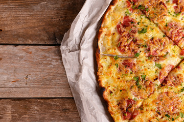 Tasty pizza on paper on wooden background
