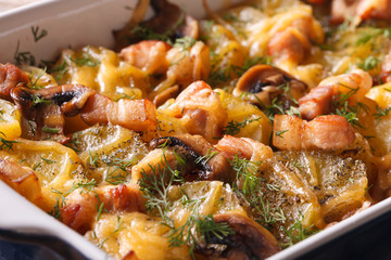 Hot potato with bacon, mushrooms and cheese in baking dish