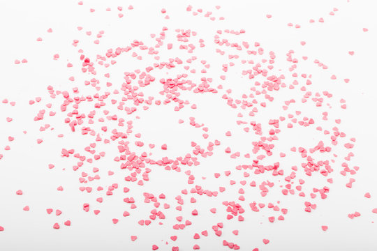 Many pink sugar hearts are scattered on a light background