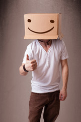 Young man gesturing with a cardboard box on his head with smiley