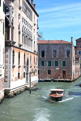 Narrow canal among old colorful brick houses in Venice, Italy.