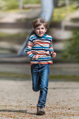 Fototapeta premium portrait of young kid running and smiling in the park