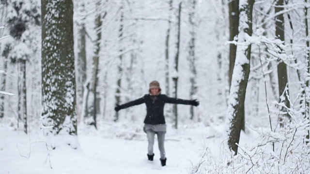 Girl running in a snowy forest, slow motion