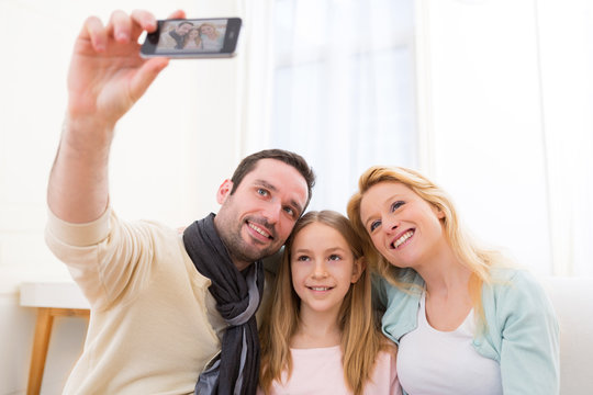 Happy family in a sofa taking selfie