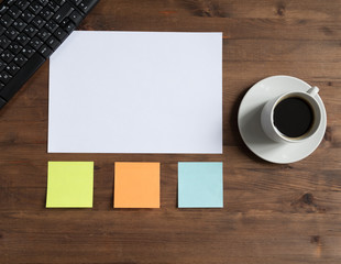 keyboard, colored stickers and cup of coffee  on the board.