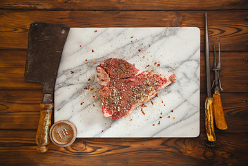 beef steak t-bone with vintage meat fork on marble backdrop