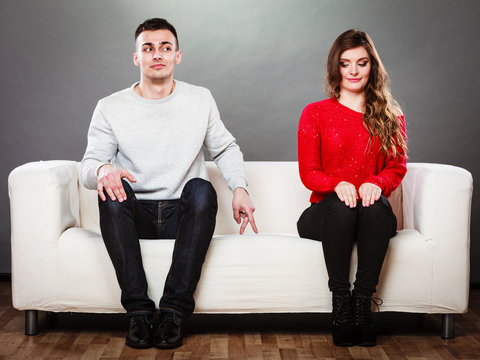 Shy woman and man sitting on sofa
