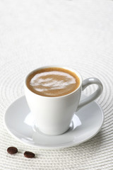 cup of coffee in a saucer  on white wicker a mat