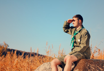 Boy Scout Sitting on Rock Watching Over the Field