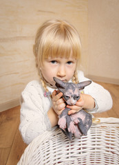 Obraz premium Little blond girl holding a sphynx kitten