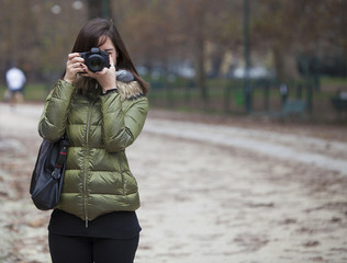 Beautiful girl holding a camera and taking a picture