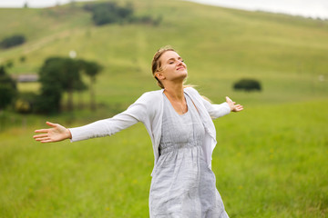 young woman with arms open on grassland