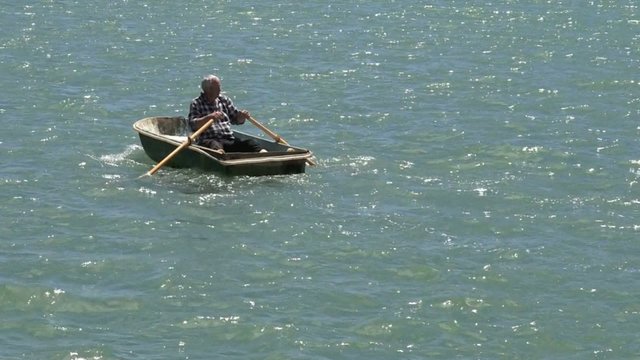 Slow motion of a man rowing a row boat at sea