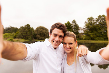Obraz premium couple taking selfie together by the lake