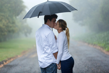young couple in love under umbrella in the rain
