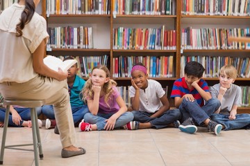 Cute pupils and teacher having class in library