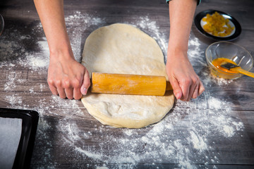 Closeup of dough being flattened on a wooden cutting 