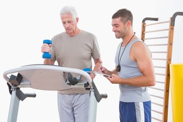 Senior man on treadmill with trainer