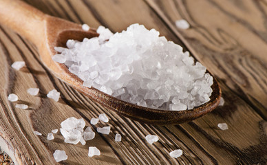 Salt in spoon on  a wooden  table.