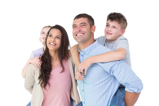 Happy parents giving piggyback ride to children while looking up