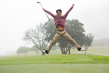 Fototapeta na wymiar Excited golfer jumping up and smiling at camera
