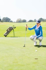 Obraz premium Female golfer watching her ball on putting green