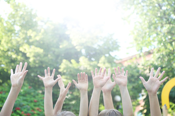 People showing hands up on sunny natural background