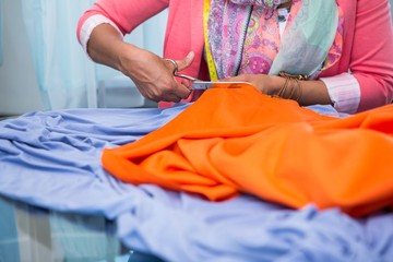 Hands cutting fabric at table