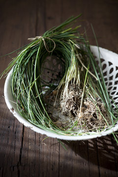 bunch of wild chives on white basket on wooden table