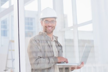Fototapeta na wymiar Smiling male architect using laptop in office