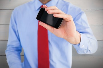 Composite image of hand of businessman showing smartphone