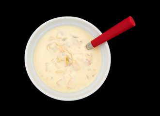 Bowl of clam chowder with a spoon on a black background