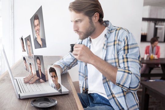 Composite image of casual man using laptop drinking espresso