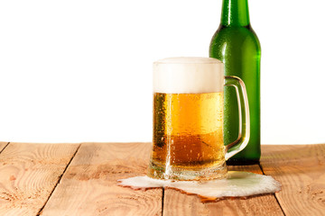 Bottle, glass and spilled beer on wooden table.Isolated
