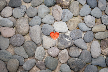 Red paper heart on the pebble stone floor