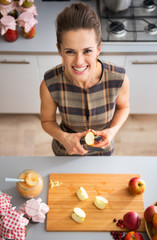 Portrait of happy young housewife cutting apple for jam