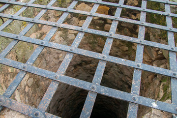 Very deep old water well with grid.
