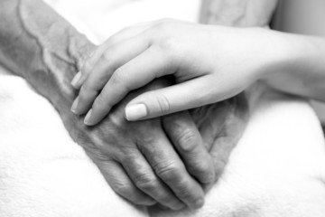 Hands of the old man and a young woman.Black and white