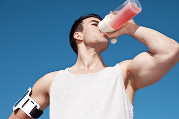 Young and handsome athlete drinking protein cocktail