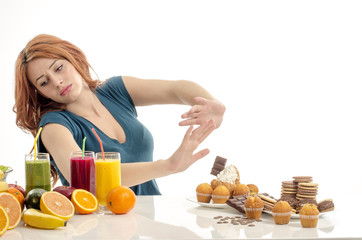 Woman choosing between fruits, smoothie,healthy food and sweets